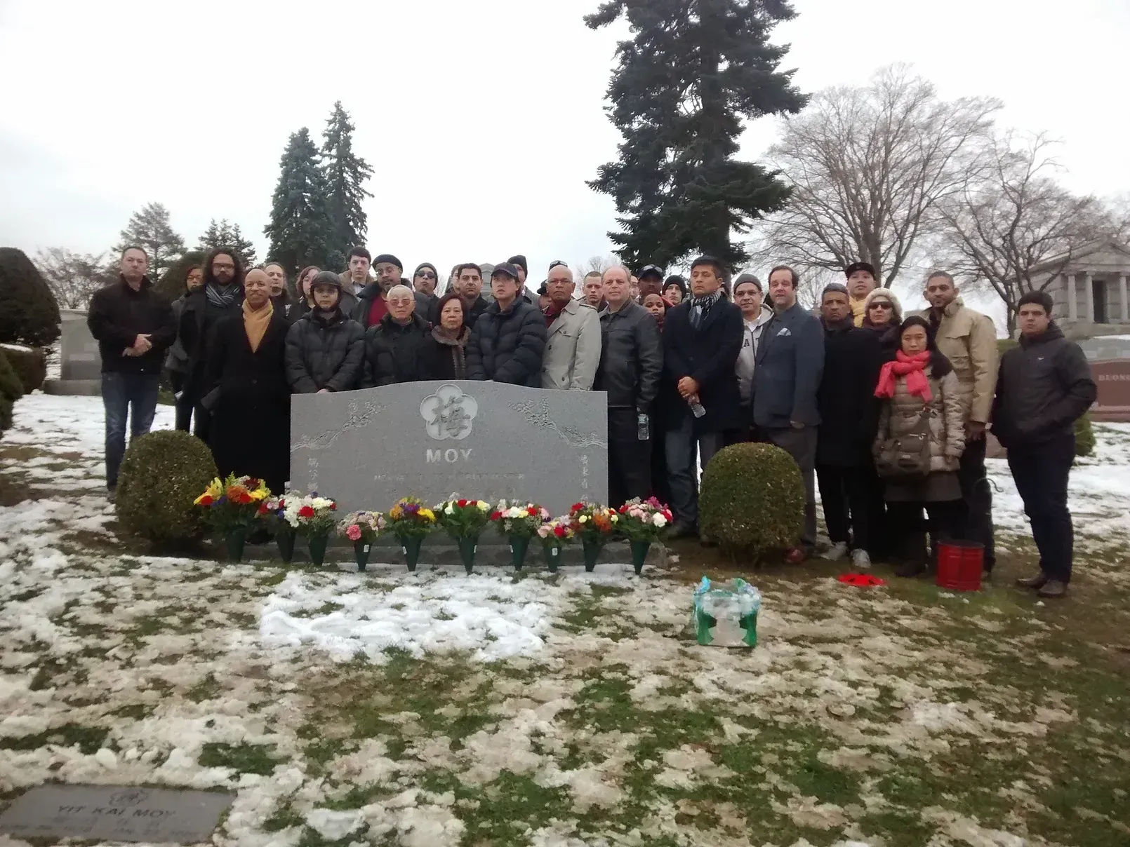 A group of people are posing for a picture in front of a grave