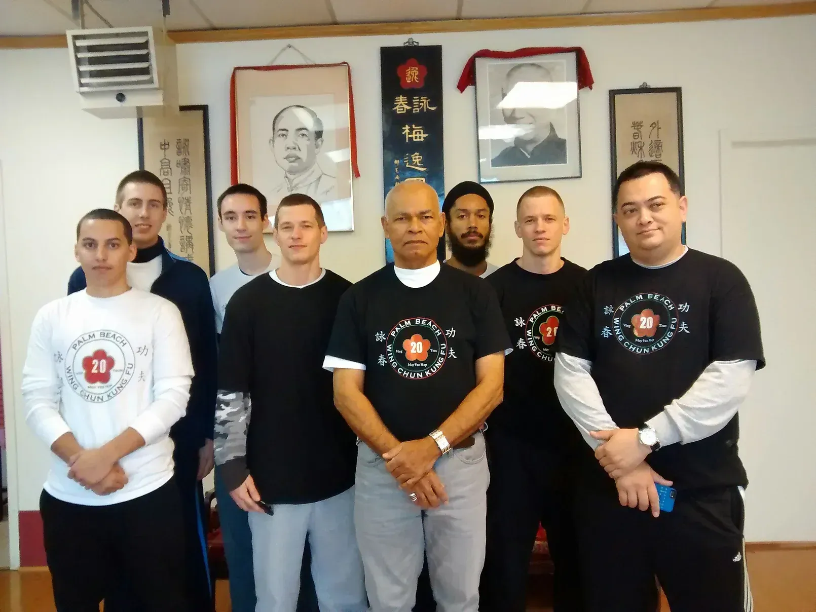 A group of men are posing for a picture with one man wearing a shirt with the letter b on it