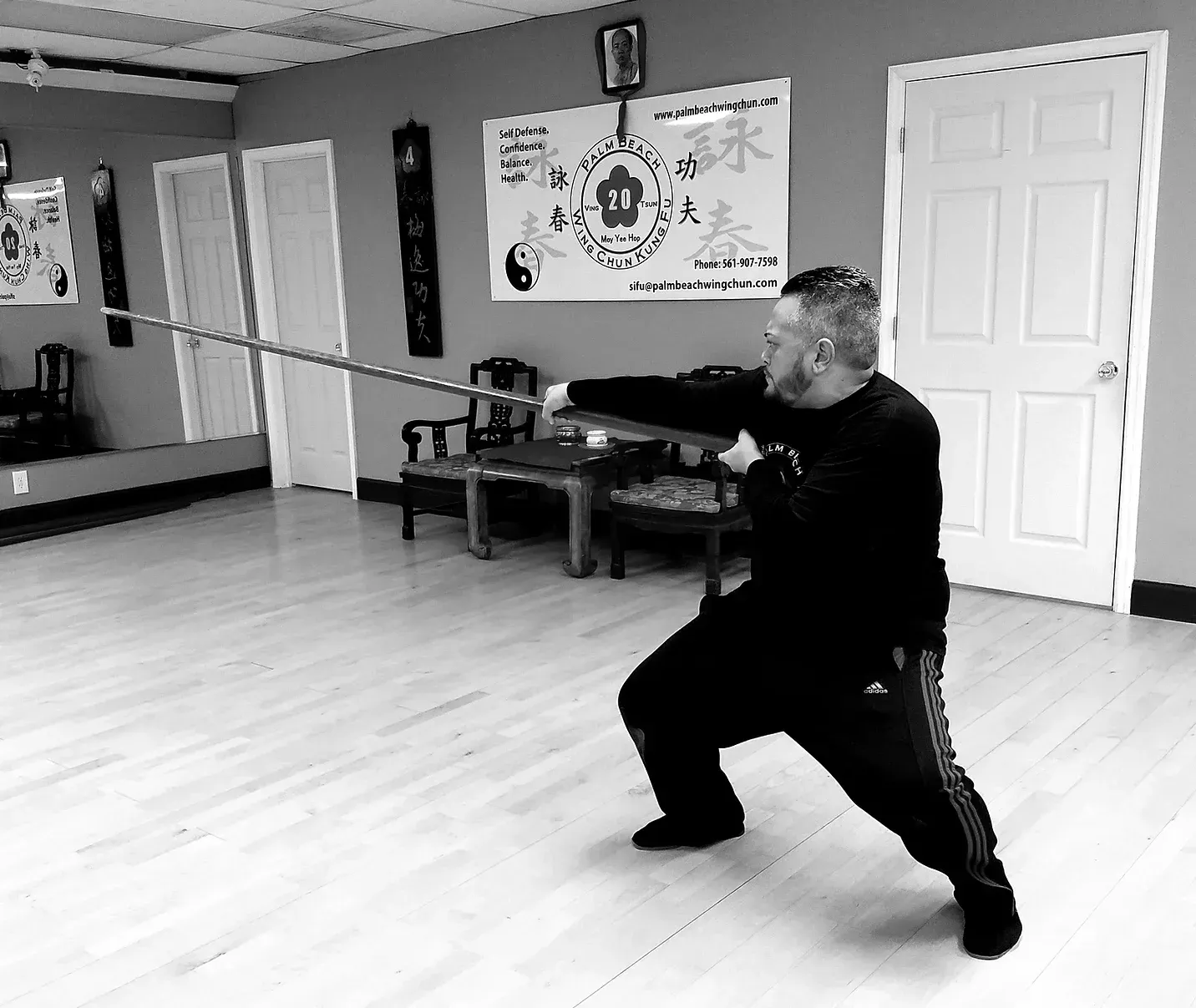 A man is holding a long stick in a room.