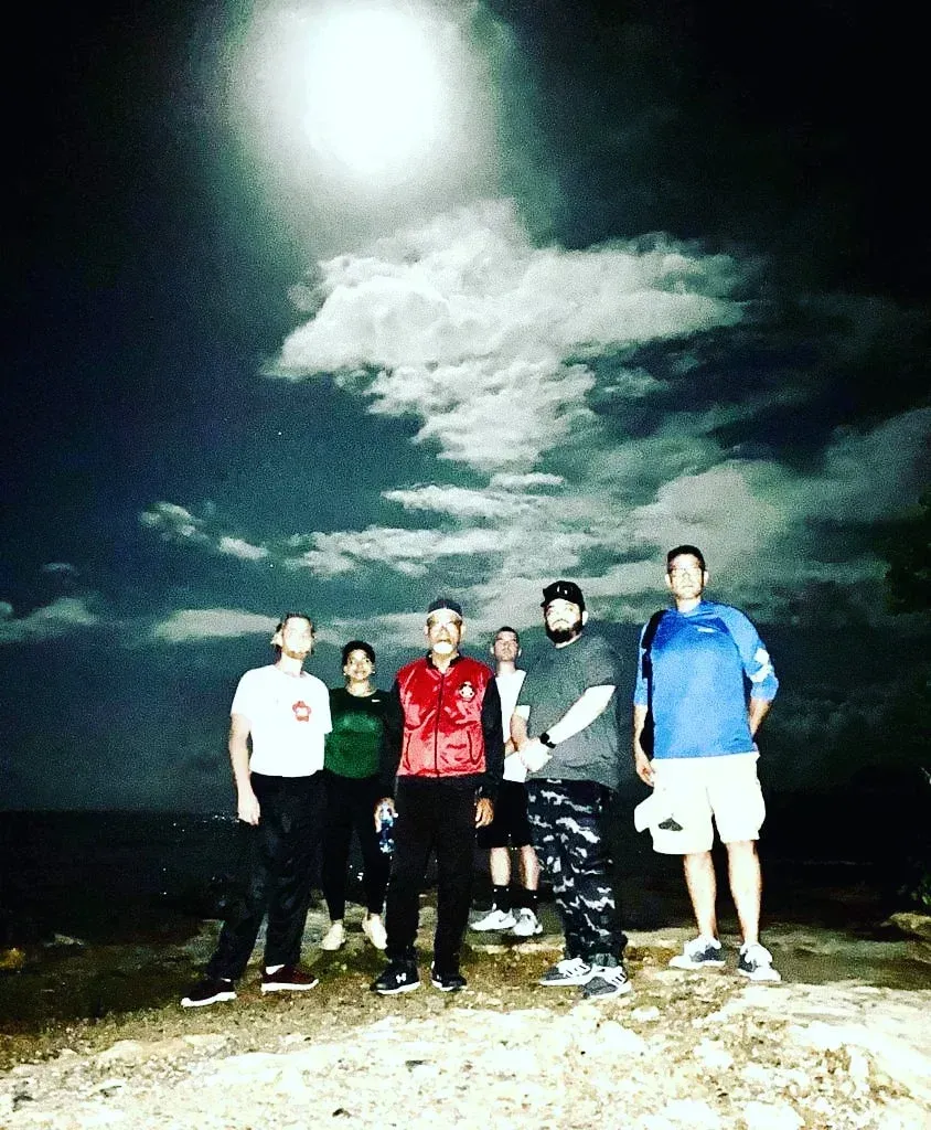 A group of people standing in front of a full moon