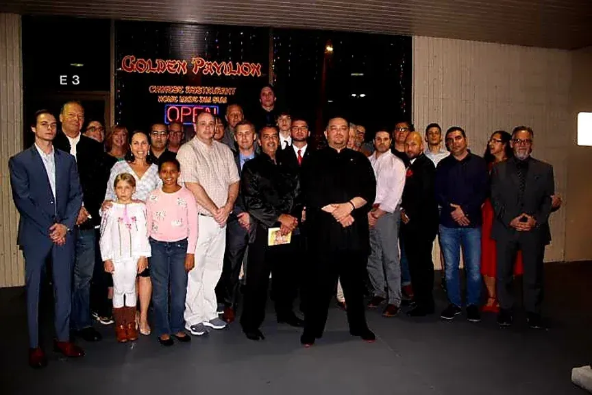 A large group of people are posing for a picture in front of a building that says open