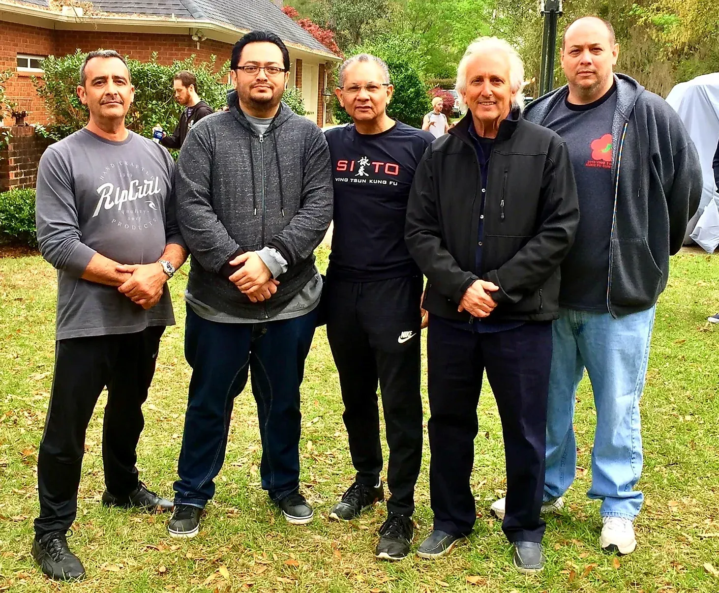 A group of men are posing for a picture in front of a house.