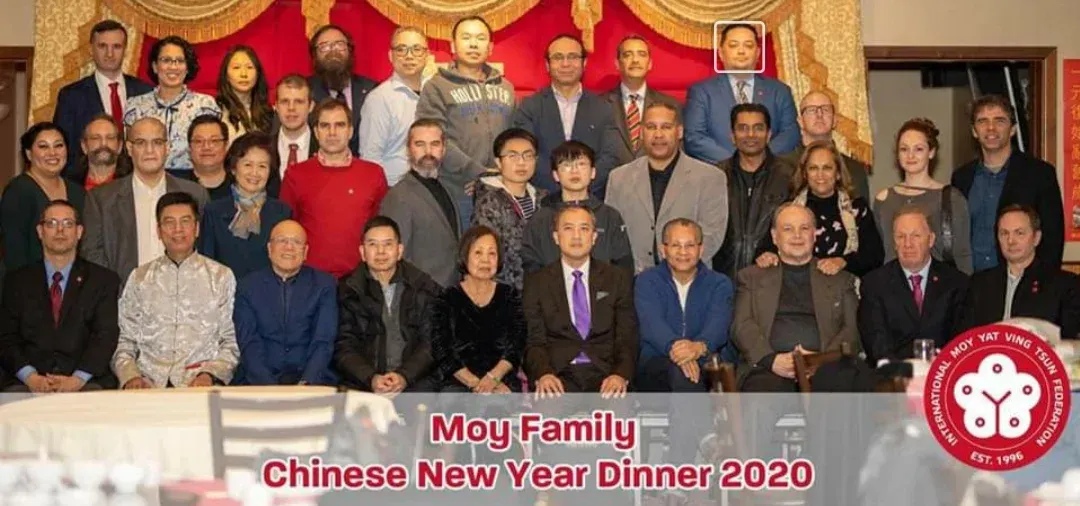 A group of people are posing for a picture at a chinese new year dinner.