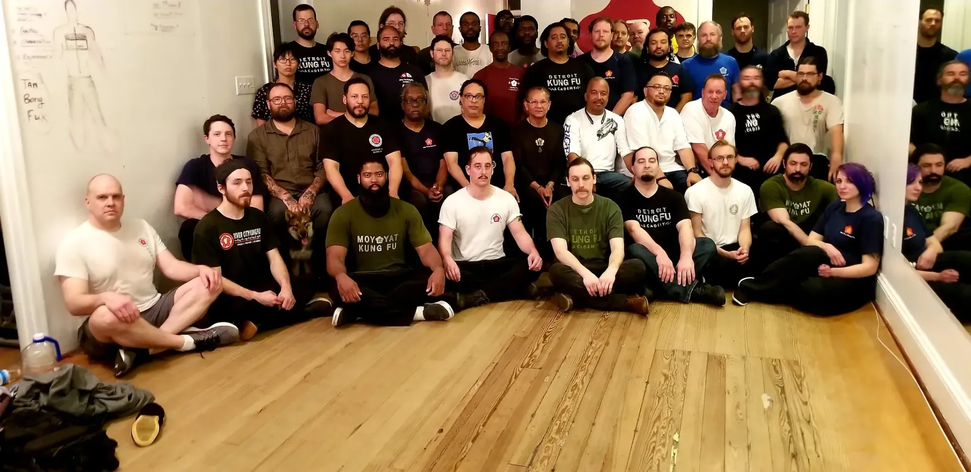 A large group of people are sitting on the floor posing for a picture.