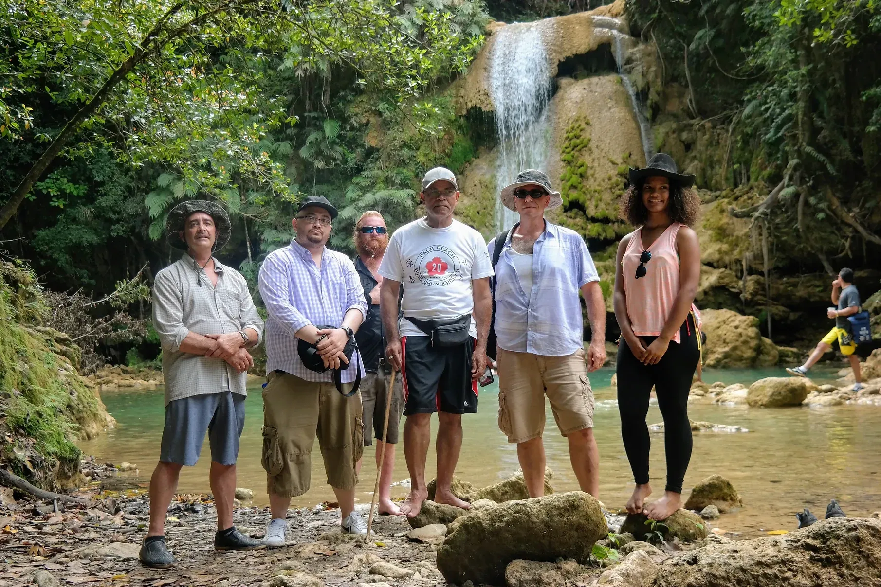 A group of people are standing in front of a waterfall.