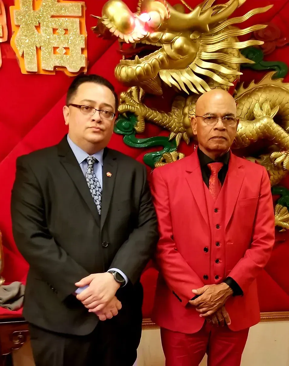Two men in suits standing in front of a dragon