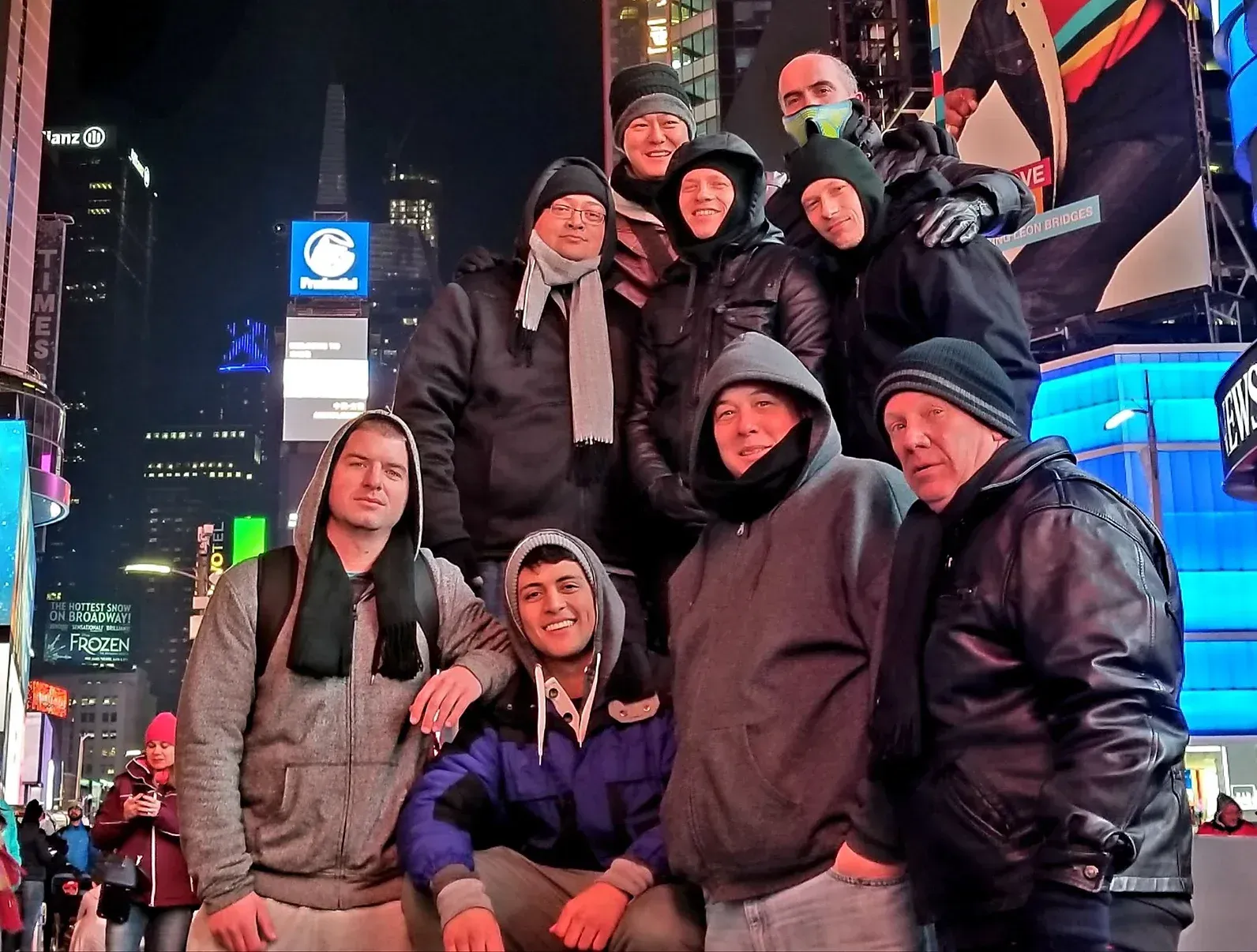 A group of people are posing for a picture in a city at night.