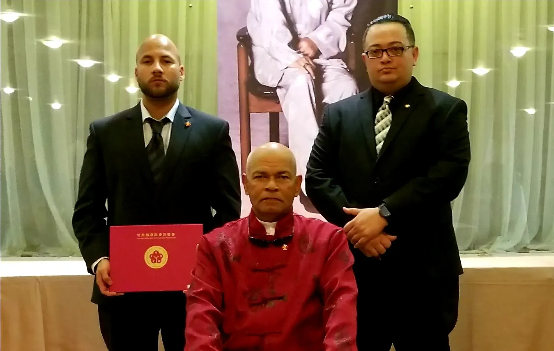 Three men in suits and ties are posing for a picture . one of the men is holding a diploma.