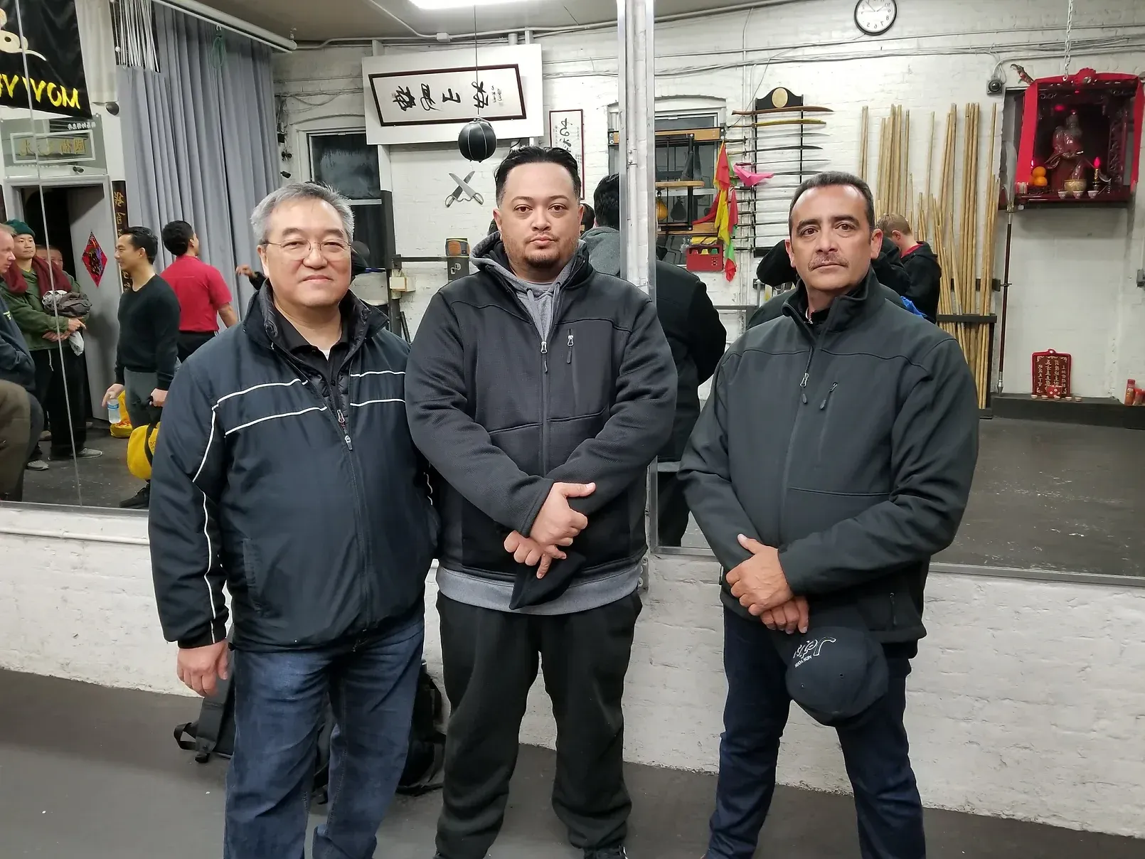 Three men are posing for a picture in front of a mirror