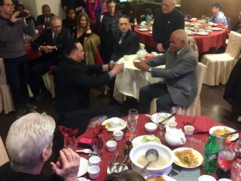A group of people are sitting around a table with food and drinks.