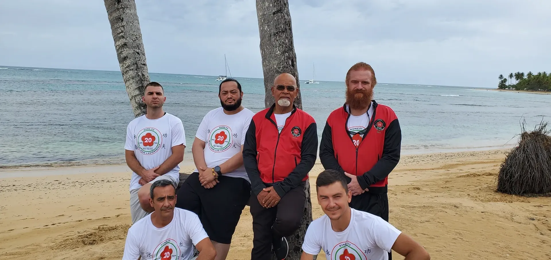 A group of men are posing for a picture on a beach.