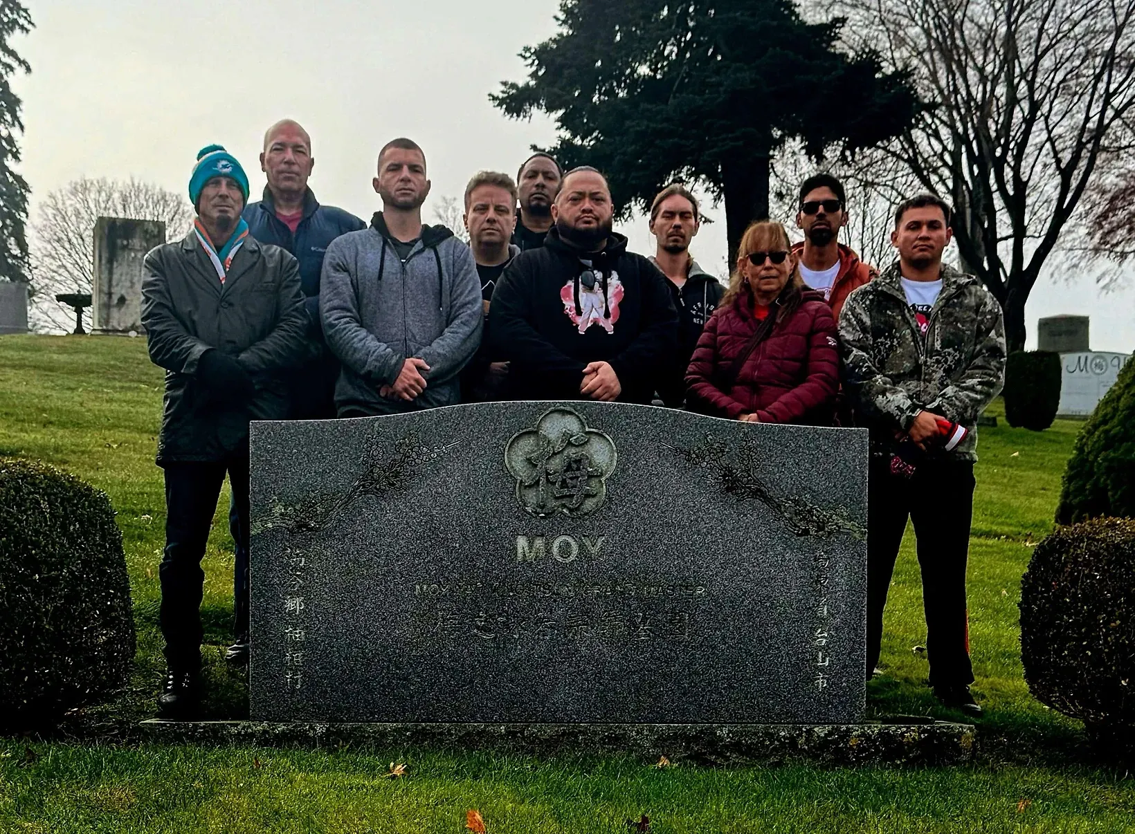 A group of people are posing for a picture in front of a grave.
