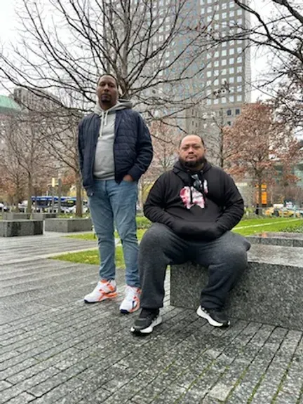 Two men are standing next to each other in a park.
