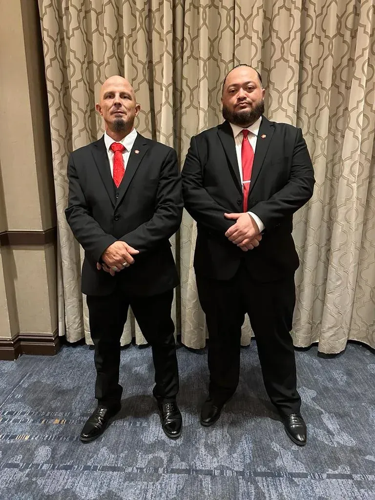 Two men in suits and ties are standing next to each other in a room.