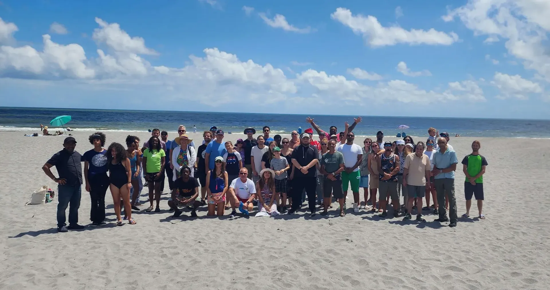 A large group of people are posing for a picture on a beach.