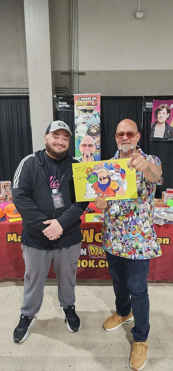 Two men are standing next to each other holding a piece of paper.