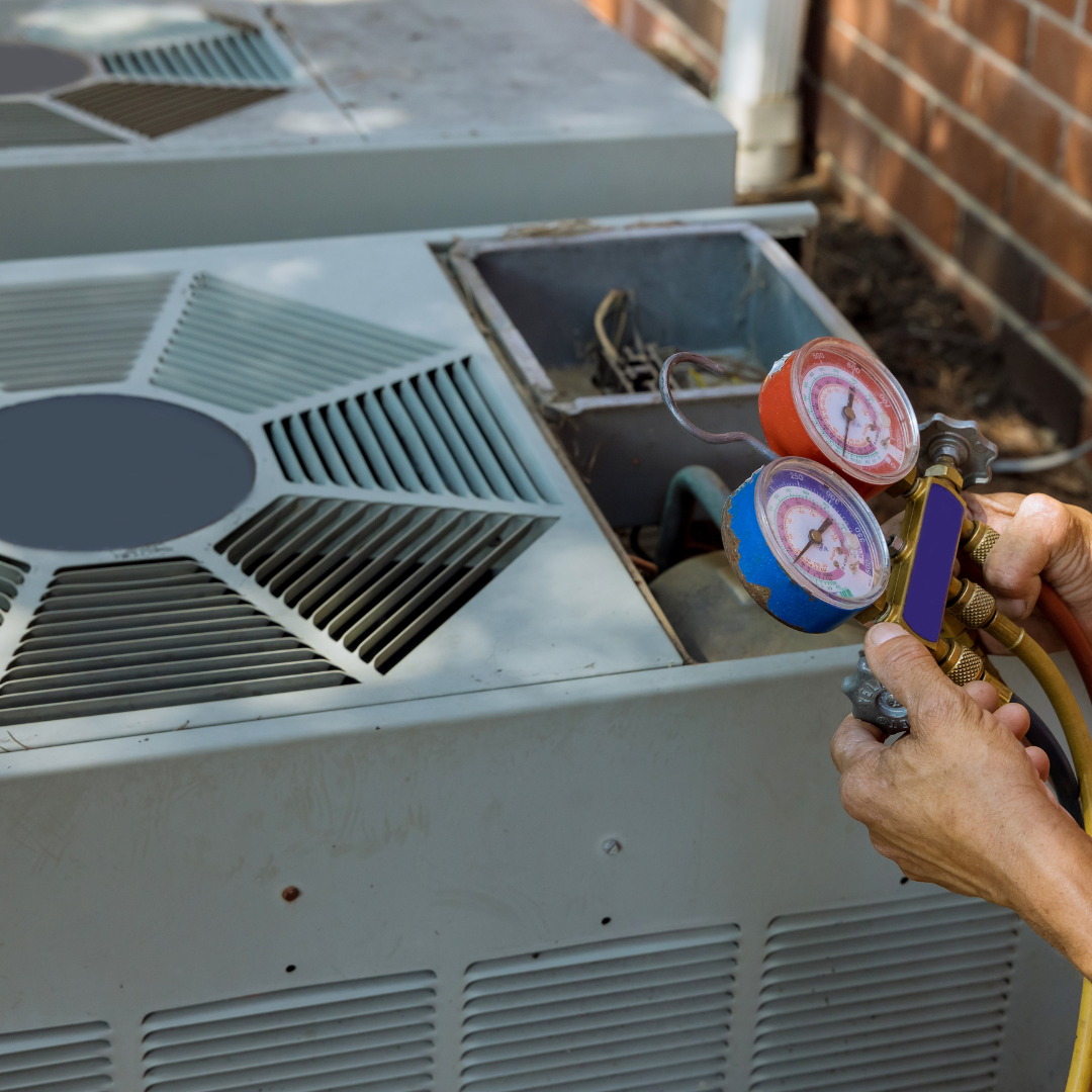 Person using gauges to service an outdoor air conditioner unit; close-up view.