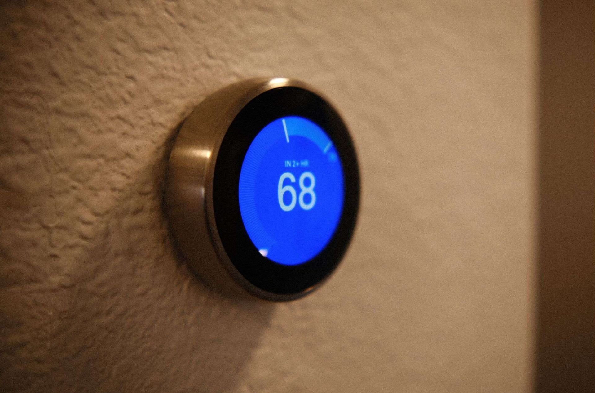 Round, blue-lit thermostat displaying