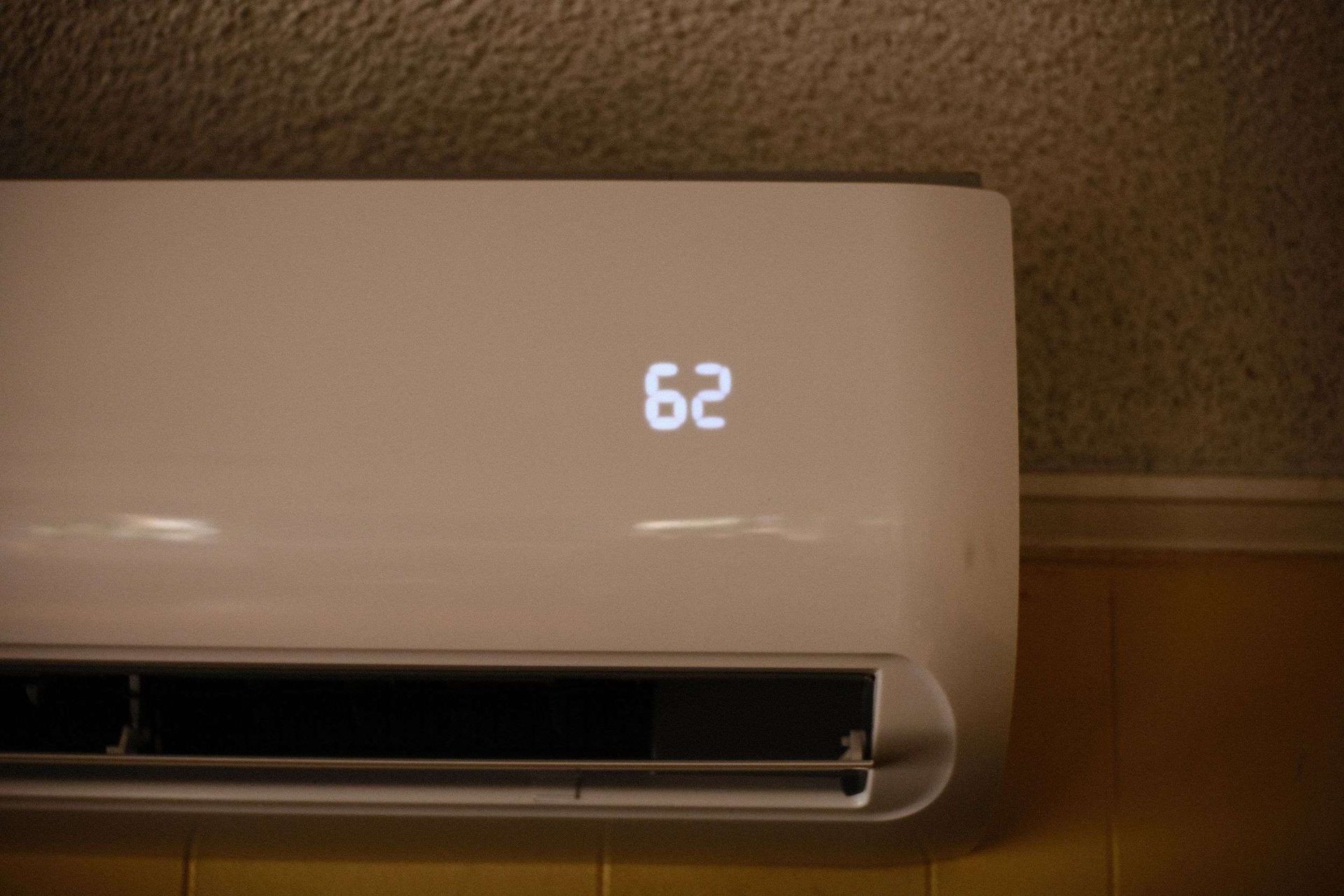 White wall-mounted air conditioner displaying the number 62.