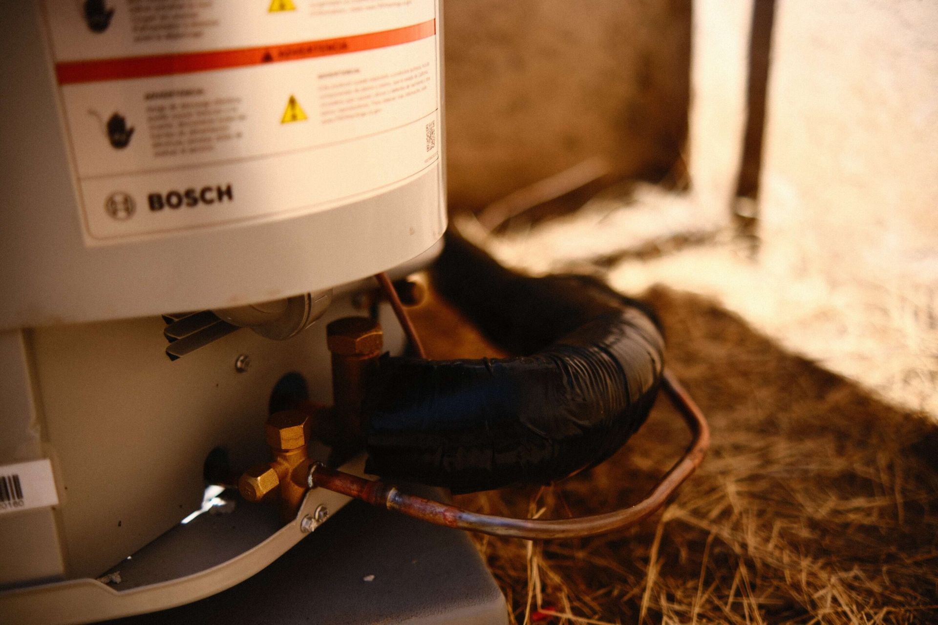 Bosch heat pump unit with copper tubing and black insulation outside.