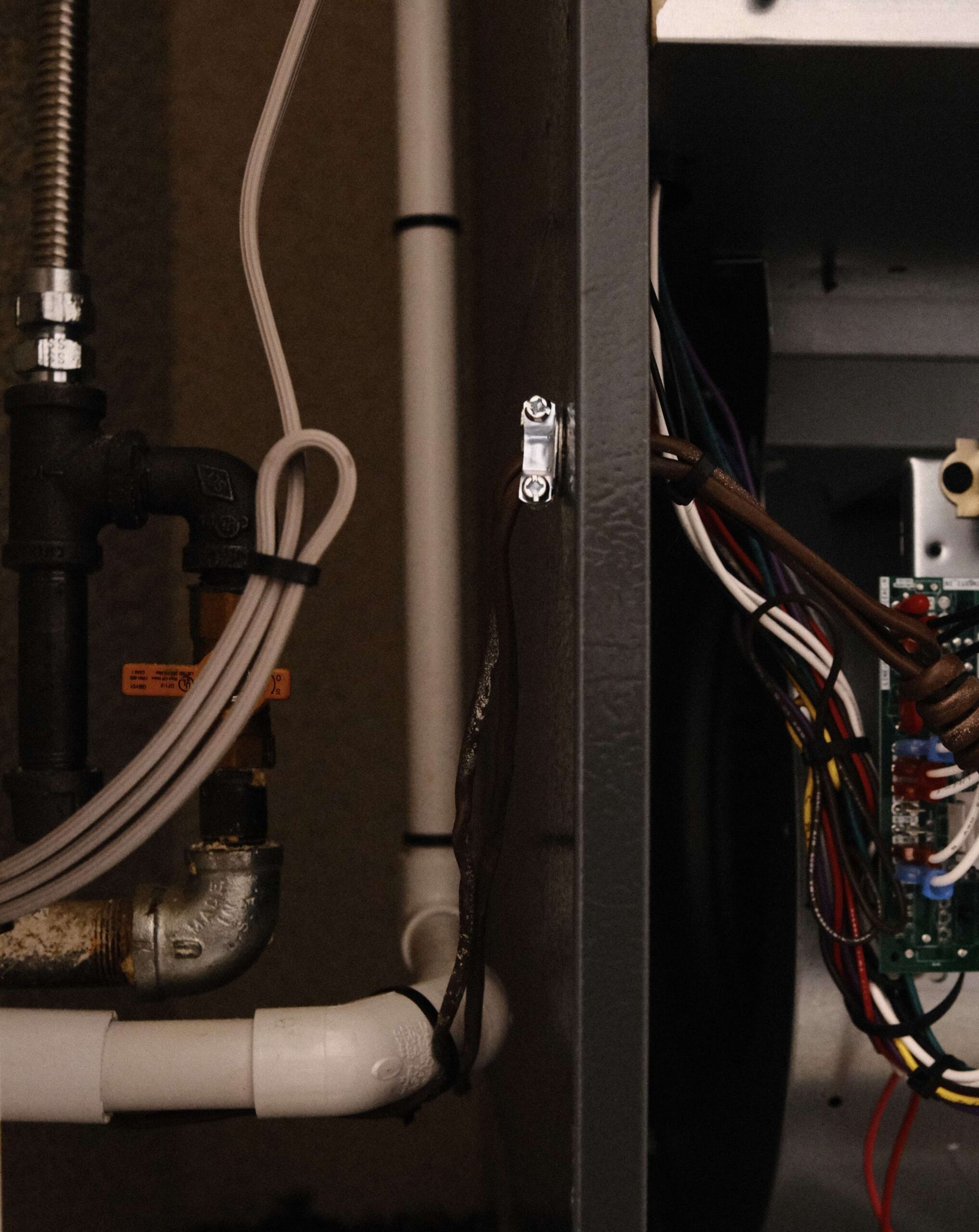 Pipes, wires, and a control box within a utility or mechanical room.