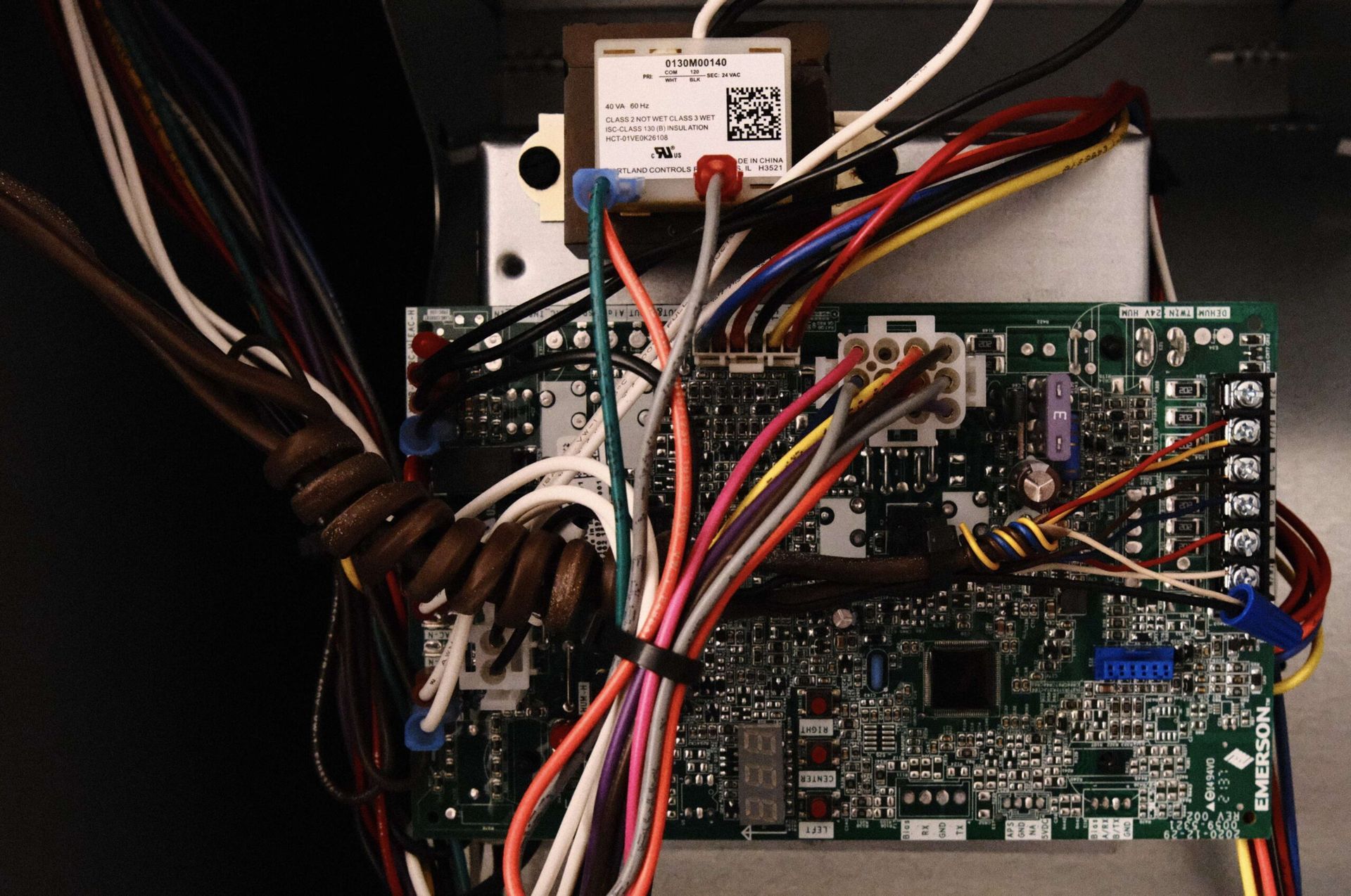 Circuit board with numerous colored wires and transformer within an appliance.