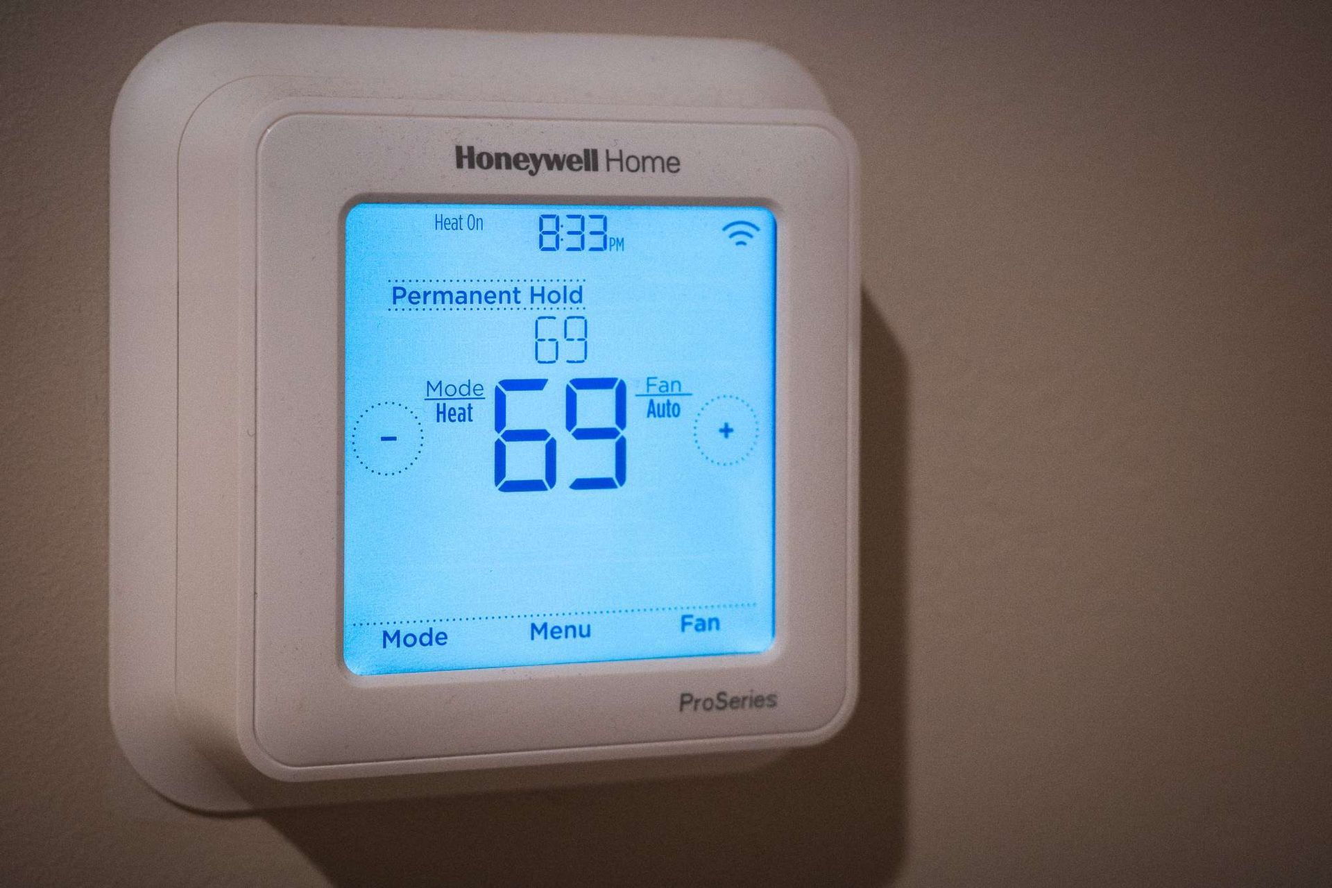 Honeywell home thermostat with a digital display showing the time.