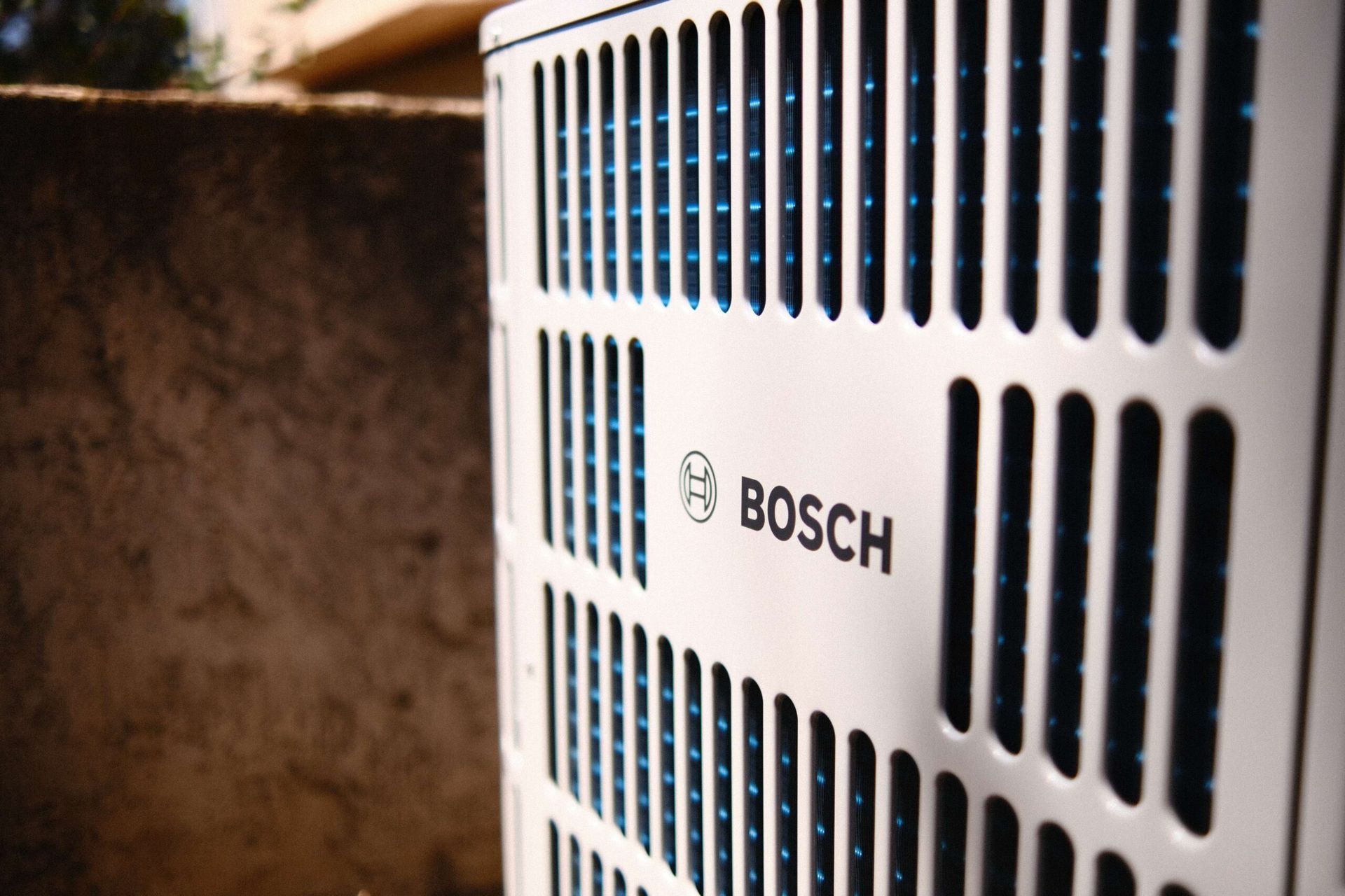 Bosch air conditioning unit with black and white grill, outdoors.
