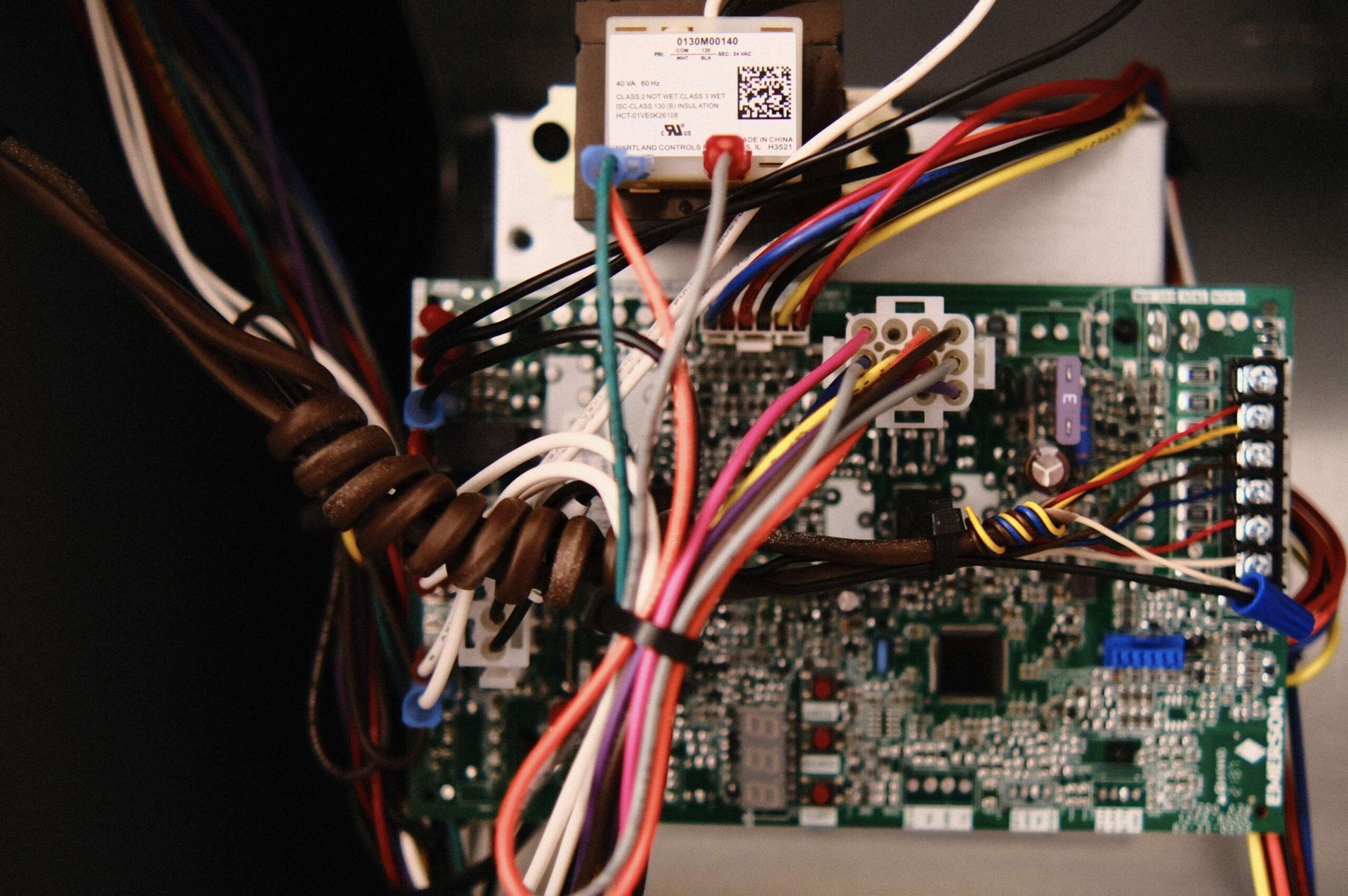 Circuit board with wires and a transformer, likely for HVAC or other electrical equipment.