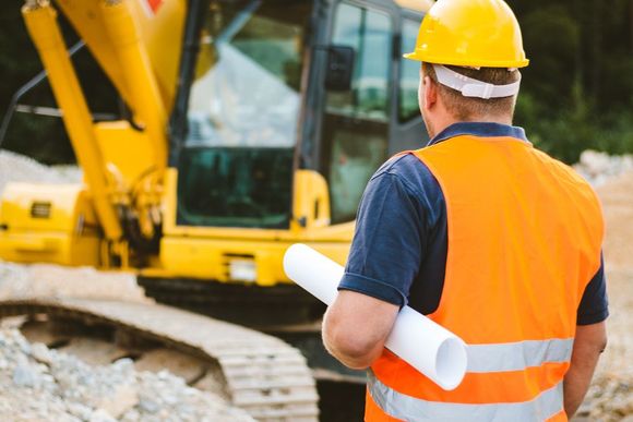 Worker Holding Blueprint On Construction Site — Annandale, MN — Alley Excavating Inc.