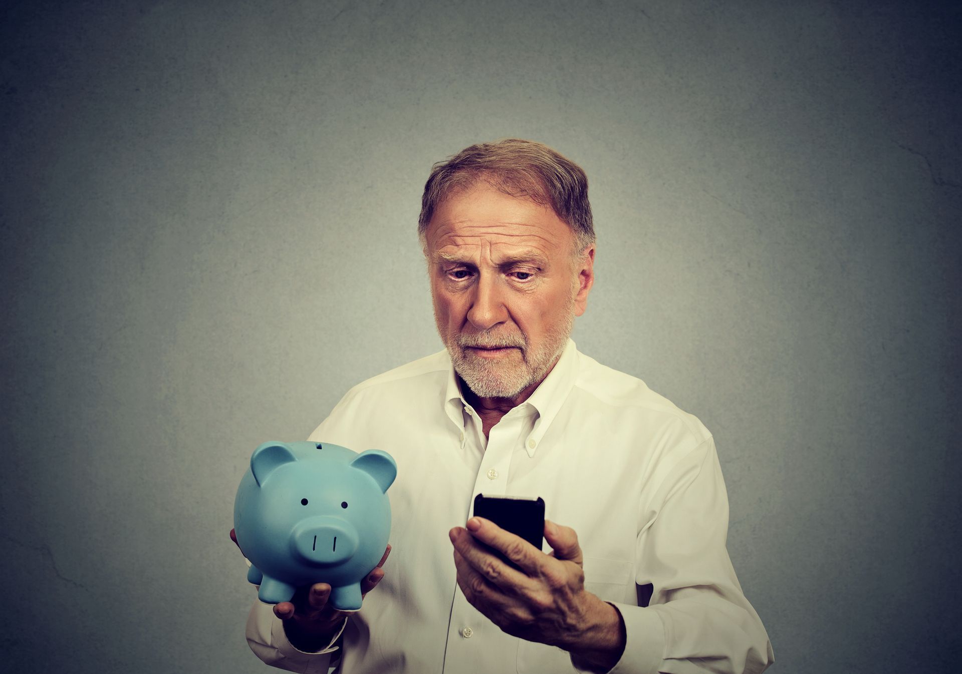 An elderly man holding a piggy bank