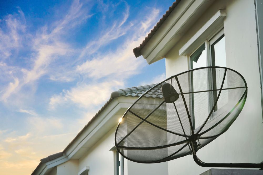 A Black Satellite Dish Mounted on A White House — Audiomation In Diamond Beach, NSW