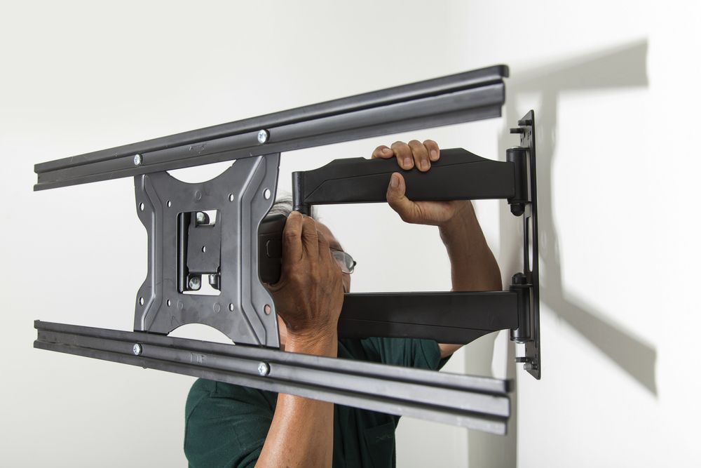 Person Installing a Tv Wall Mount Bracket on a White Wall — Audiomation in Bulahdelah, NSW