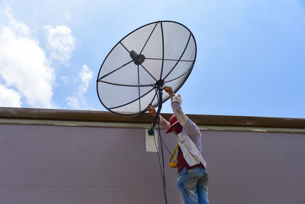A Man is Installing a Satellite Dish on the Roof of a Building — Audiomation in Taree, NSW