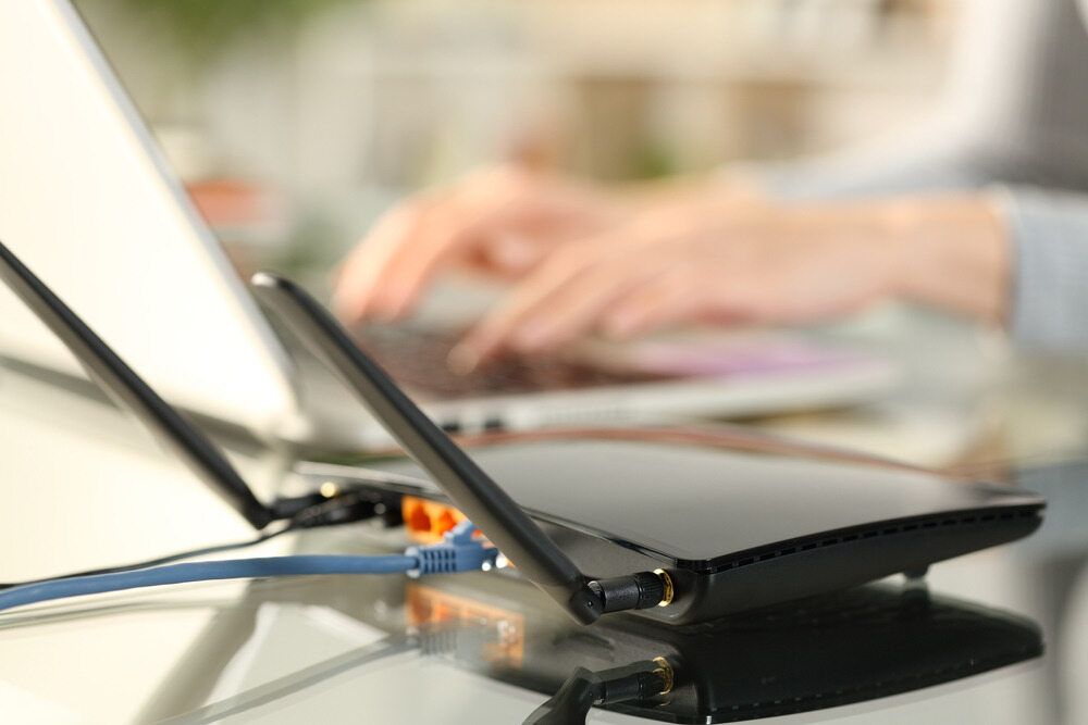 A Person is Typing on a Laptop Next to a Router — Audiomation in Taree, NSW