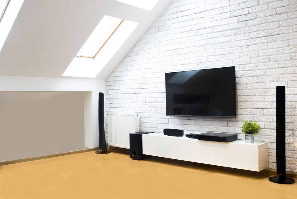 Living room with white brick wall, mounted TV, sound system, and skylight. — Audiomation In Diamond Beach, NSW