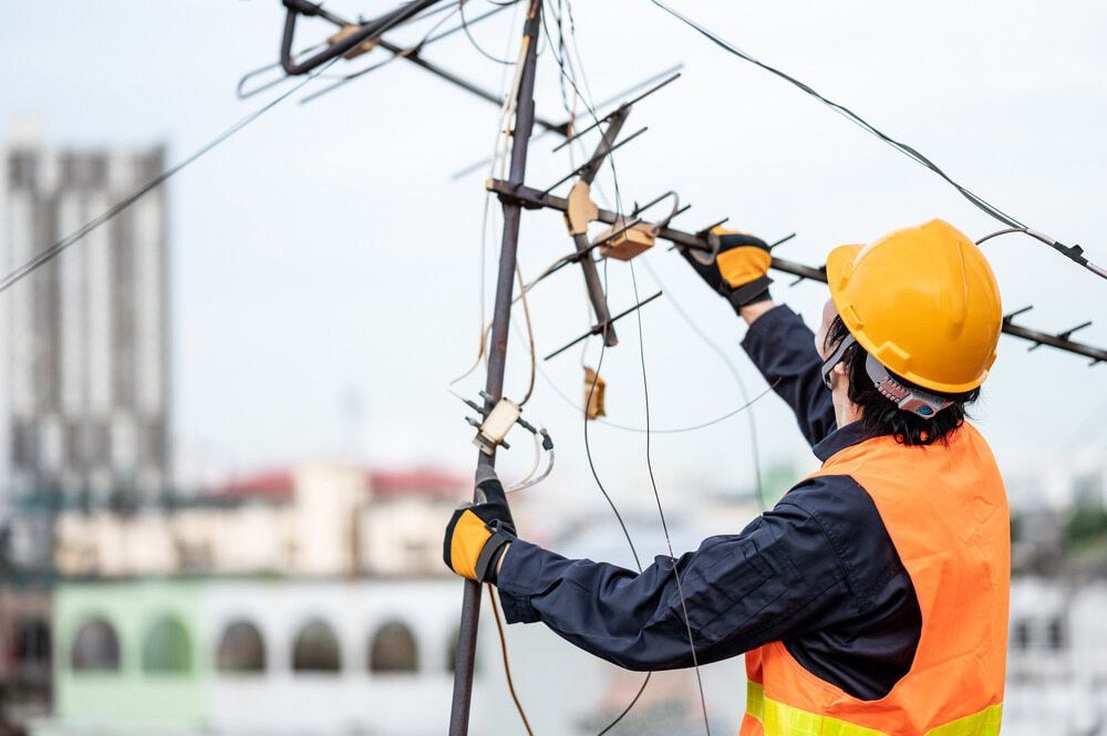 An Electrician is Working on a Power Line on Top of a Building — Audiomation in Mid North Coast, NSW