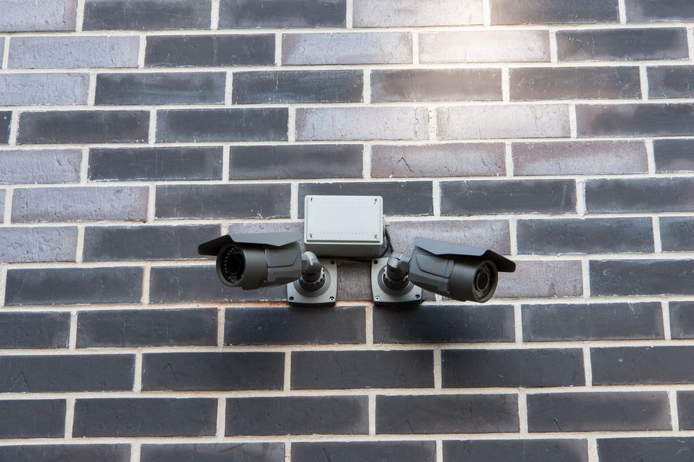Two Security Cameras Are Mounted on a Brick Wall — Audiomation in Mid North Coast, NSW