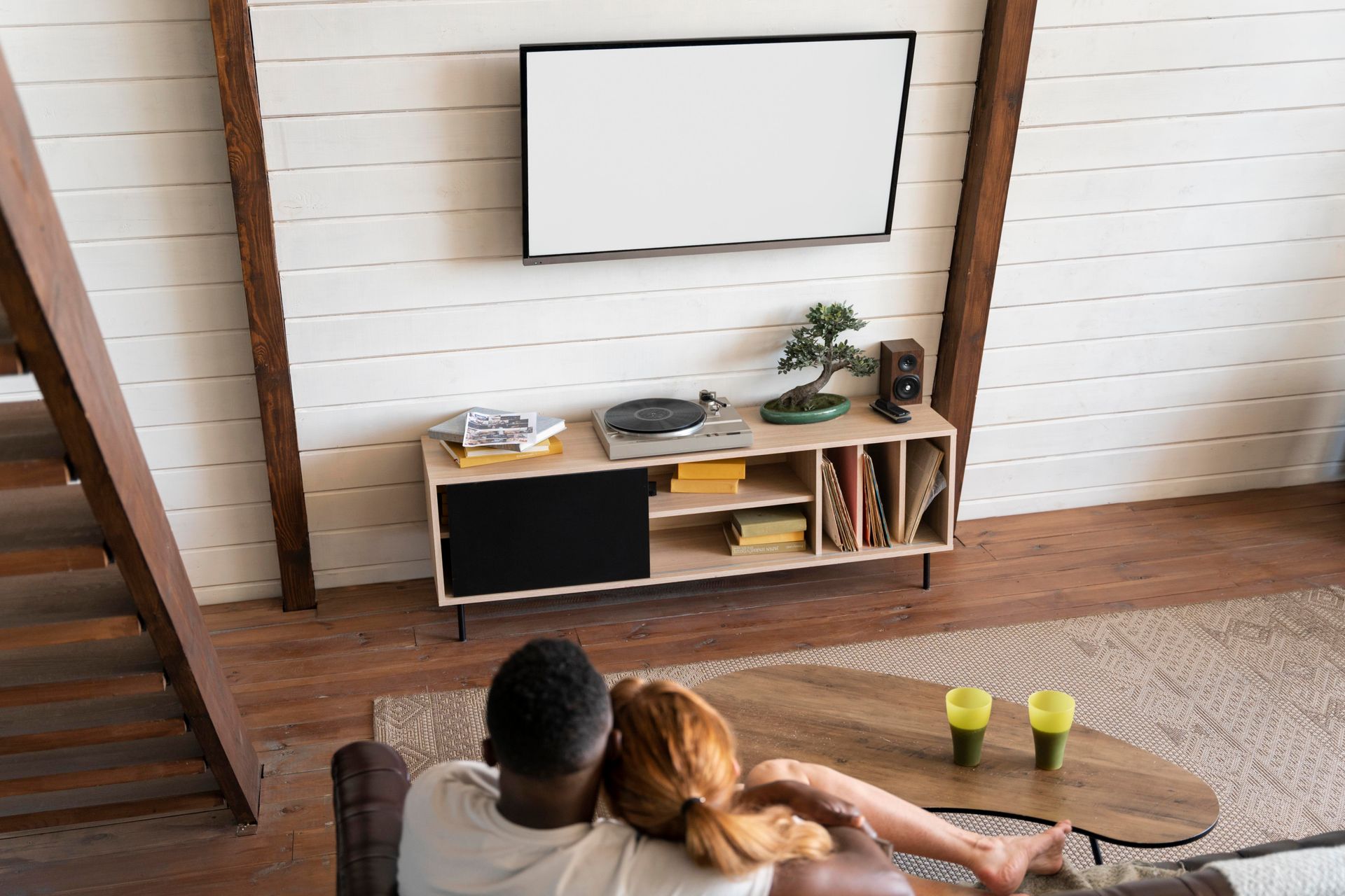 A couple sitting on the couch in front of the tv mounted on the wall — Audiomation in Nabiac, NSW