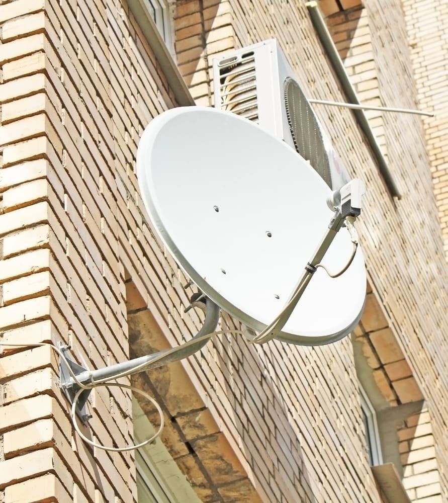 A Satellite Dish is Attached to the Side of a Brick Building — Audiomation in Taree, NSW