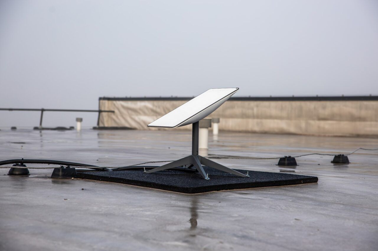 Starlink satellite dish on a flat rooftop, angled toward the sky, overcast conditions. — Audiomation in Wingham, NSW