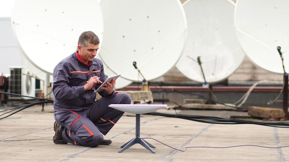 A Man is Kneeling Down on a Roof Looking at a Tablet — Audiomation in Mid North Coast, NSW