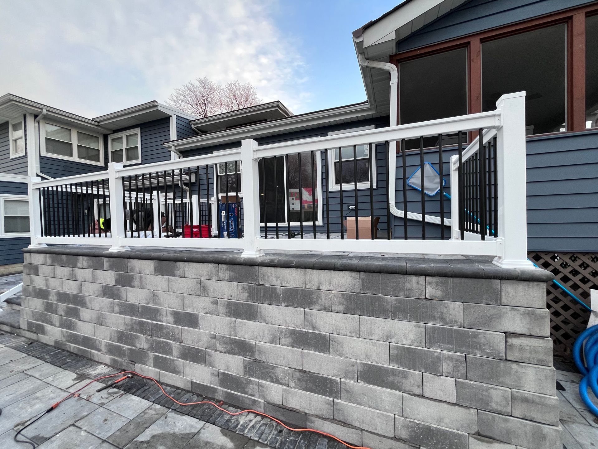 A white vinyl railing is sitting on top of a brick wall in front of a house.