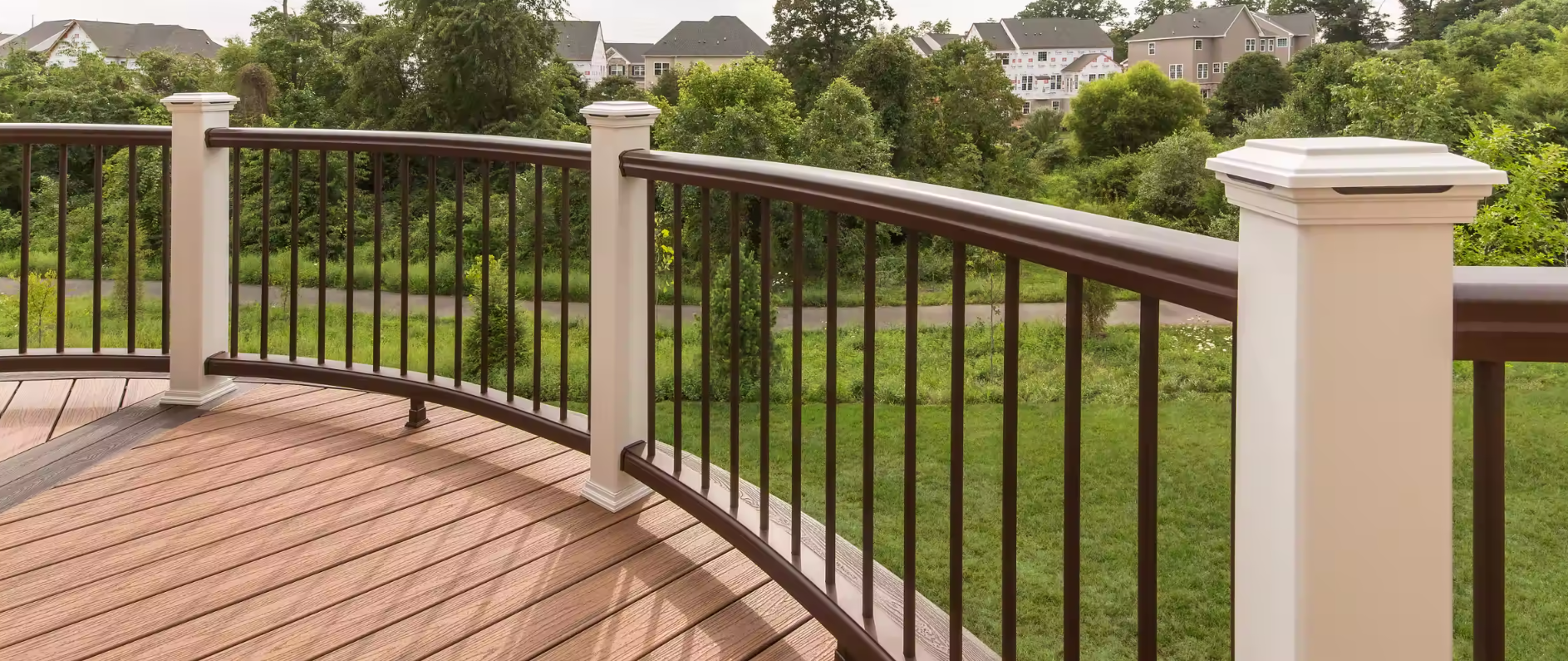 A deck with a curved railing and a view of a park.