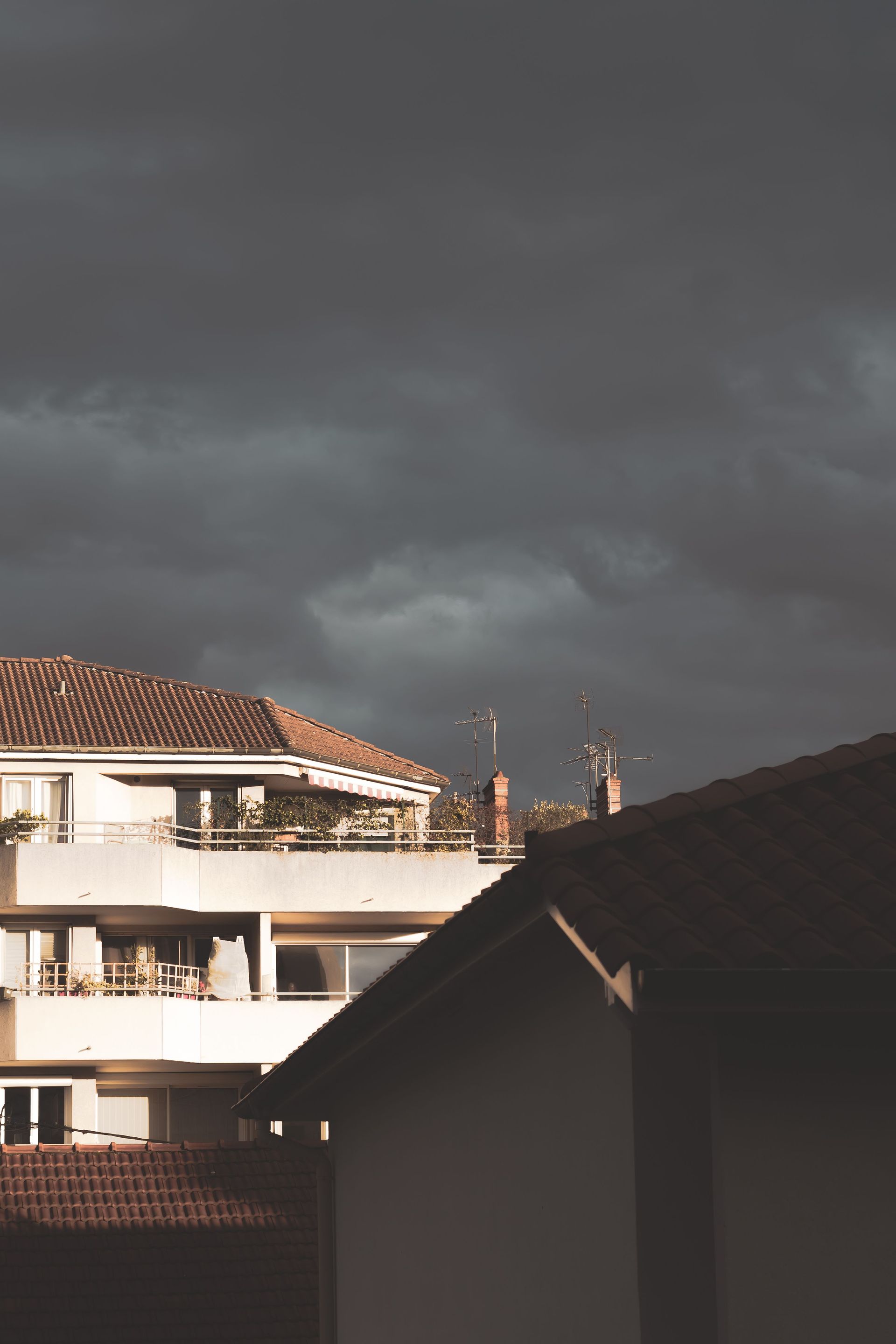 Dark stormy sky over rooftop buildings, with distant minarets visible on the horizon