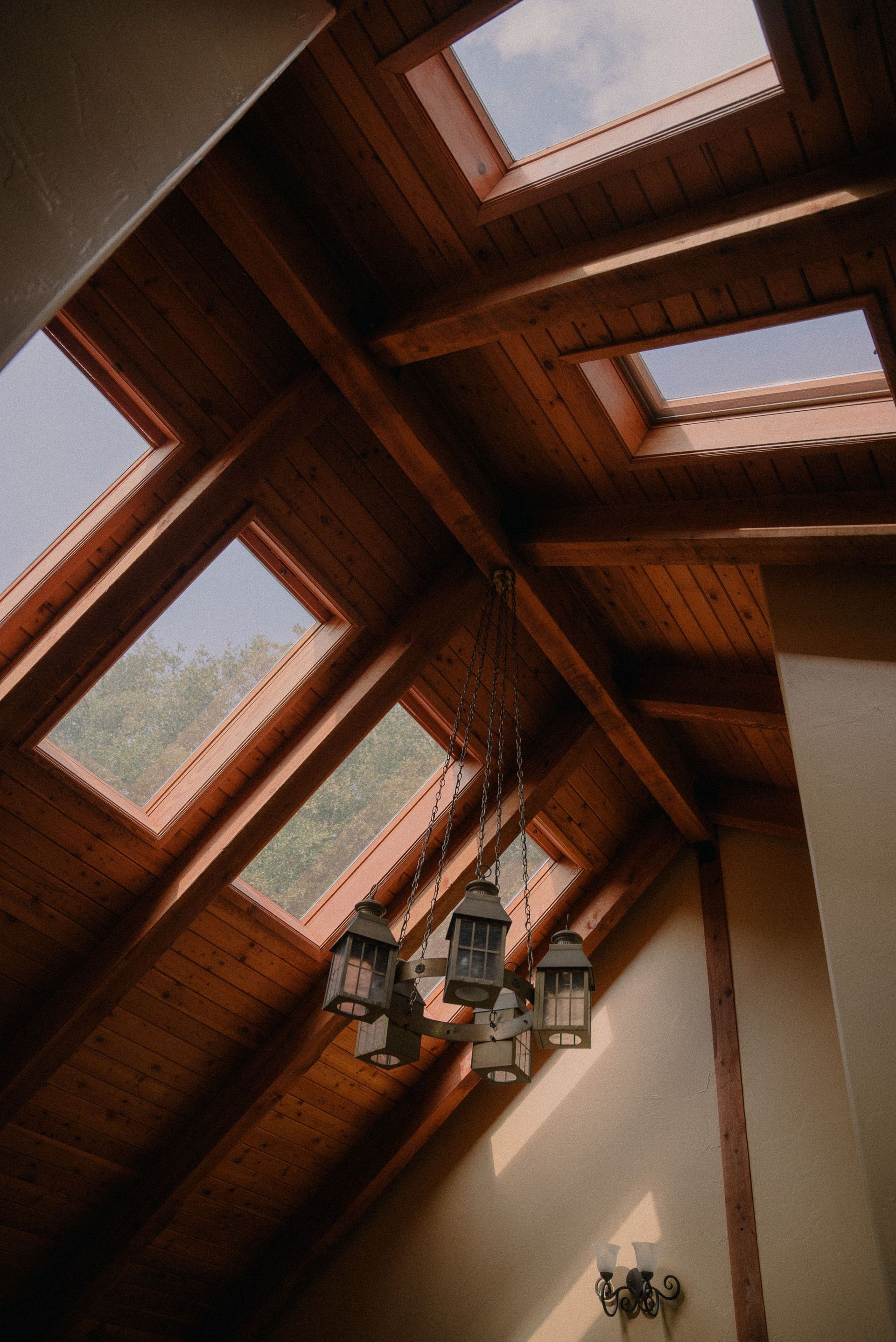 Wood-paneled skylight ceiling with skylights and hanging lanterns, viewed upward indoors