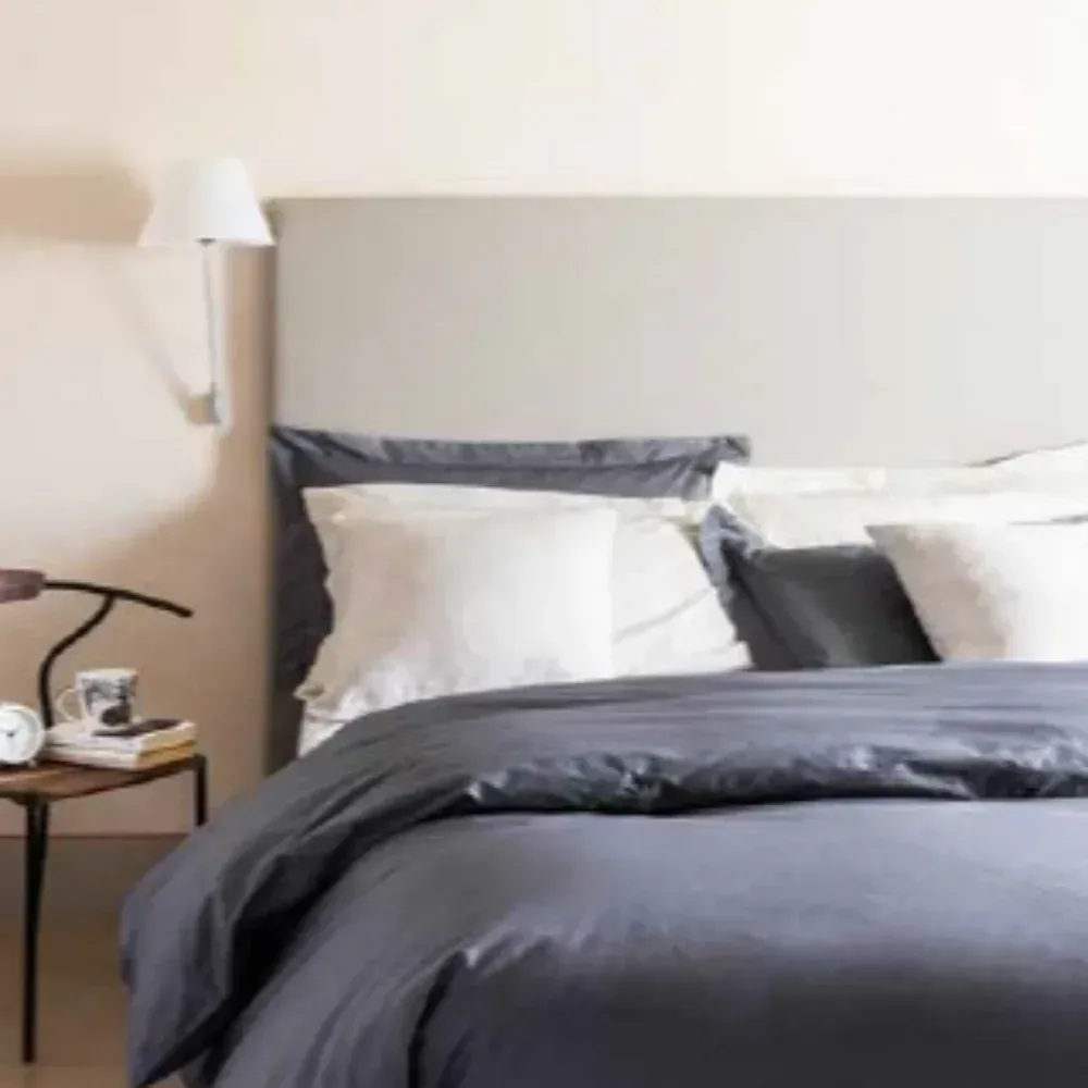 Un letto con un piumone grigio e cuscini bianchi in una camera da letto.