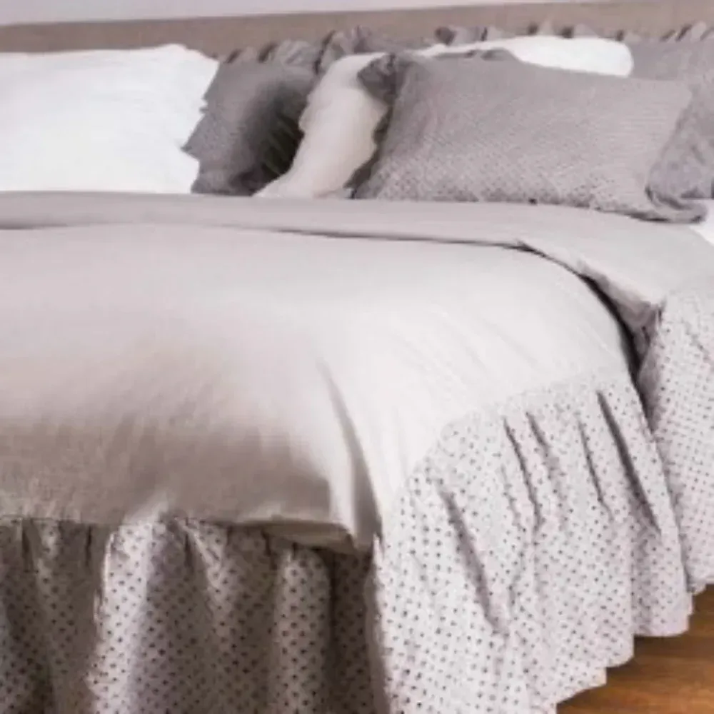 Un letto con un piumone grigio e dei cuscini sopra