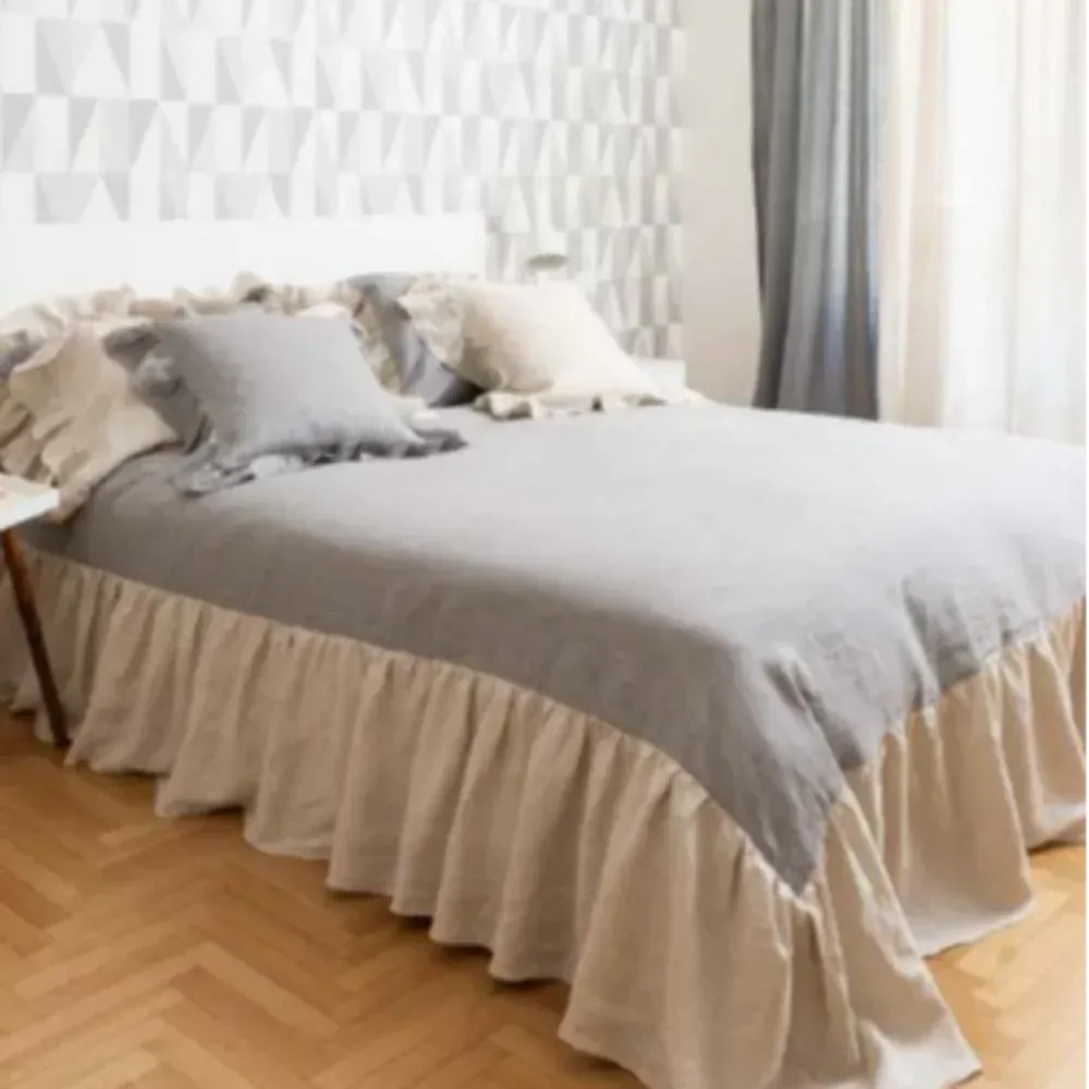 Un letto con una gonna arricciata e dei cuscini sopra