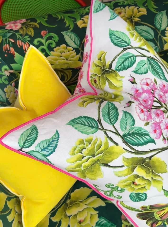 Un cuscino giallo e bianco con fiori rosa sopra